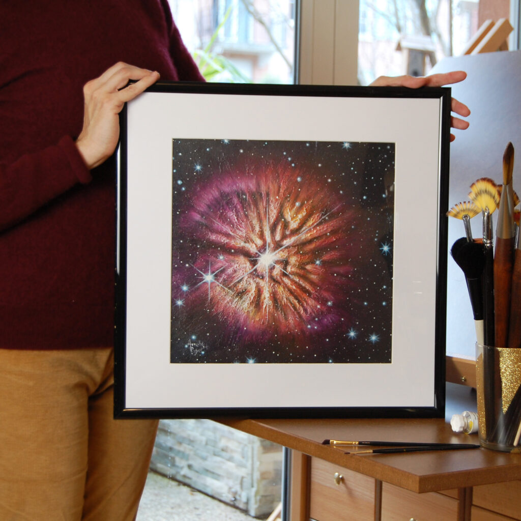 Image de la peinture à l'acrylique de l’étoile Wolf-Rayet 124 par Arielle Payet intitulée "Bloom" avec son cadre dans les mains de l'artiste à son atelier
