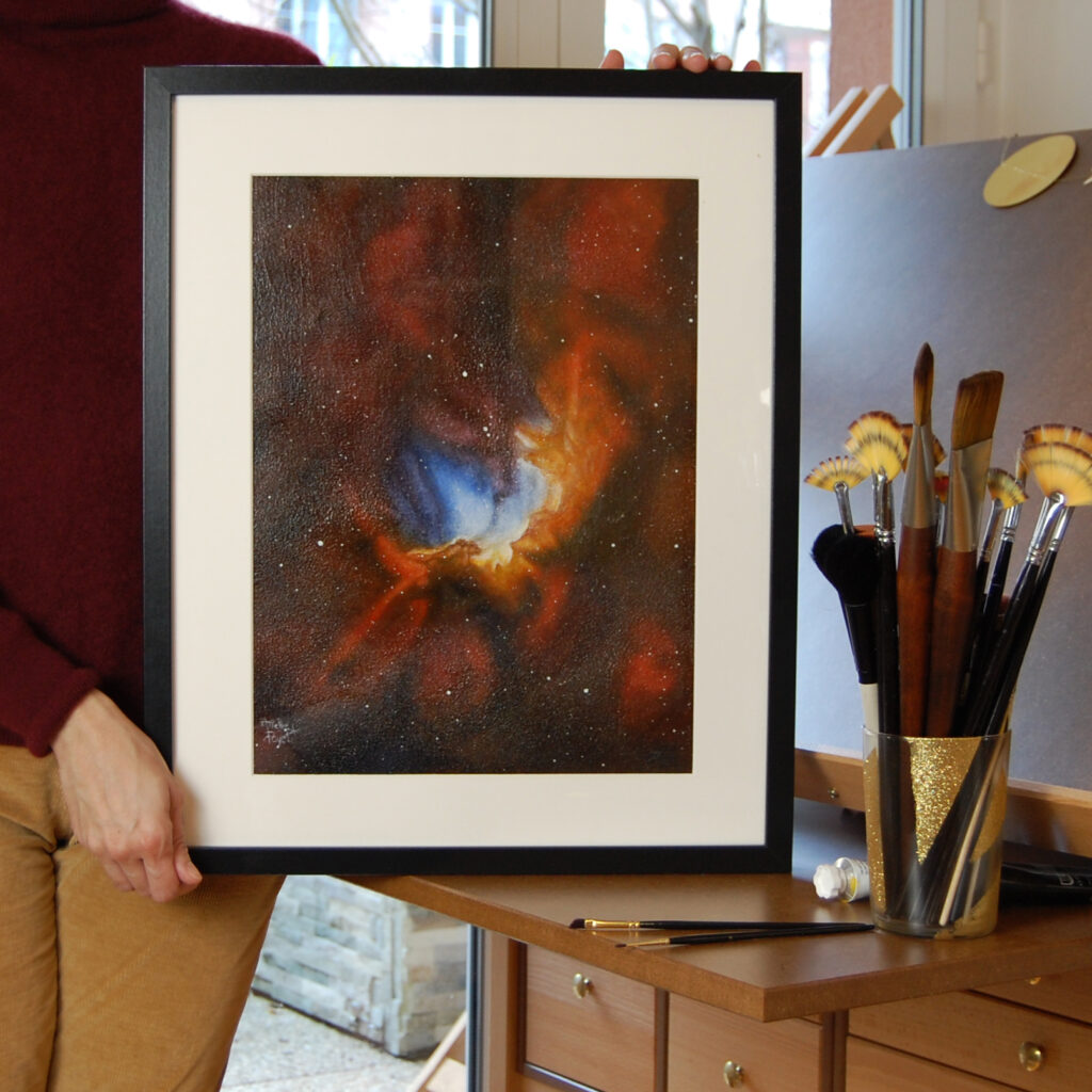 Tableau encadré de la nébuleuse du sorcier dans les mains de l'artiste Arielle Payet à son atelier