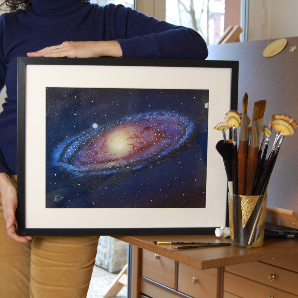 Tableau "Andromède" encadré dans les mains de l'artiste à son atelier