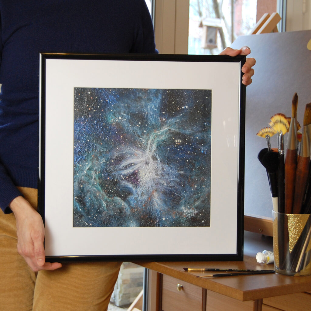 Tableau de la nébuleuse de la tarentule encadrée dans les mains de l'artiste Arielle Payet à son atelier