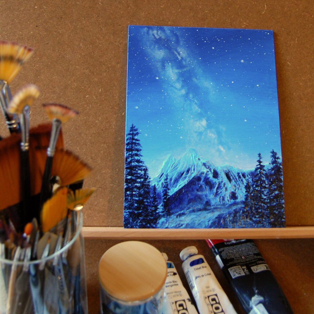Tableau "Nuit d'hiver" d'Arielle Payet représentant la voie lactée au-dessus de montagnes à l'atelier de l'artiste