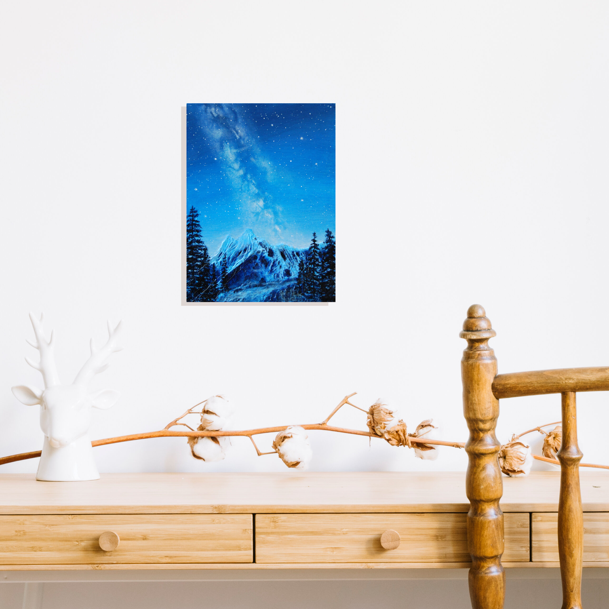 Peinture à l'acrylique de la voix lactée au-dessus d'une montagne enneigée par Arielle Payet intitulée "Nuit d'hiver" mis en situation au-dessus d'un bureau en bois
