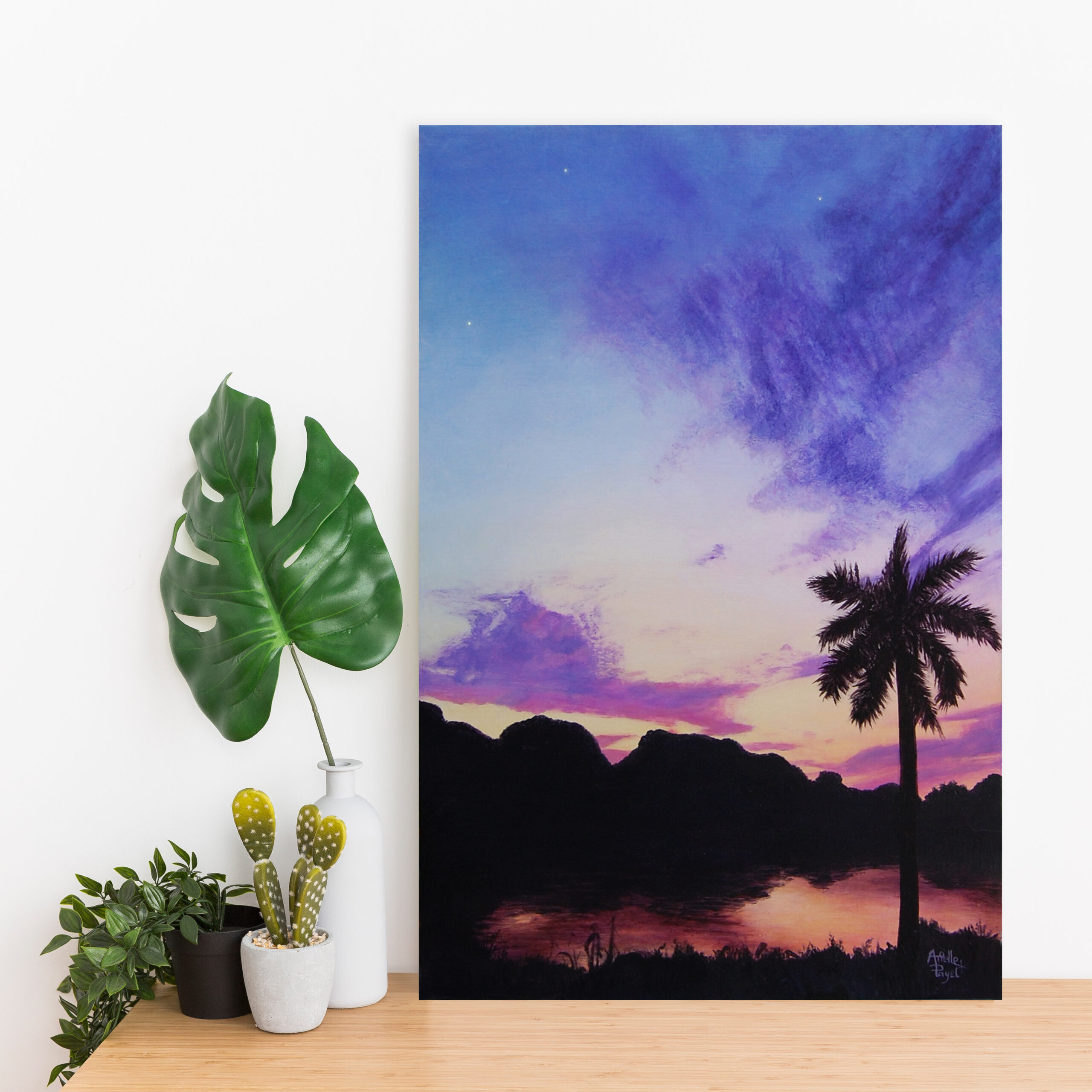 Peinture à l'acrylique intitulée "Nuit d'Indochine" par Arielle Payet montrant un coucher de soleil sur un lac mis en situation sur un bureau