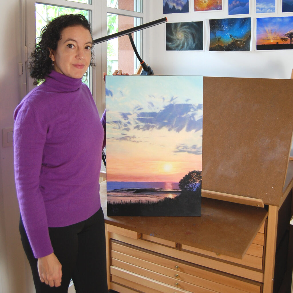 Arielle Payet à son atelier tenant la peinture à l'acrylique intitulée "21h33 sur l'estran"